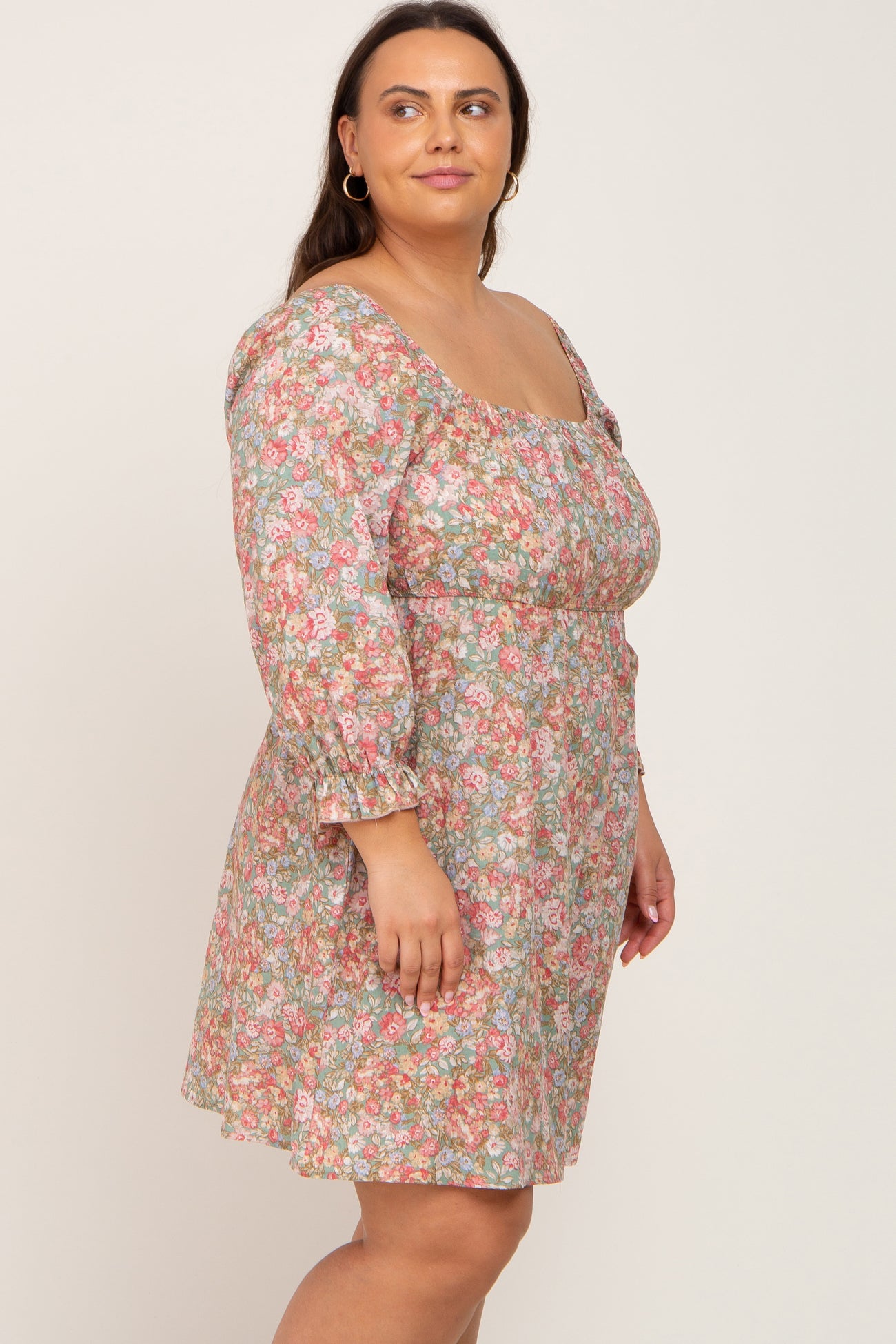 woman wearing a floral plus size dress with three-quarter sleeves and a fitted waist