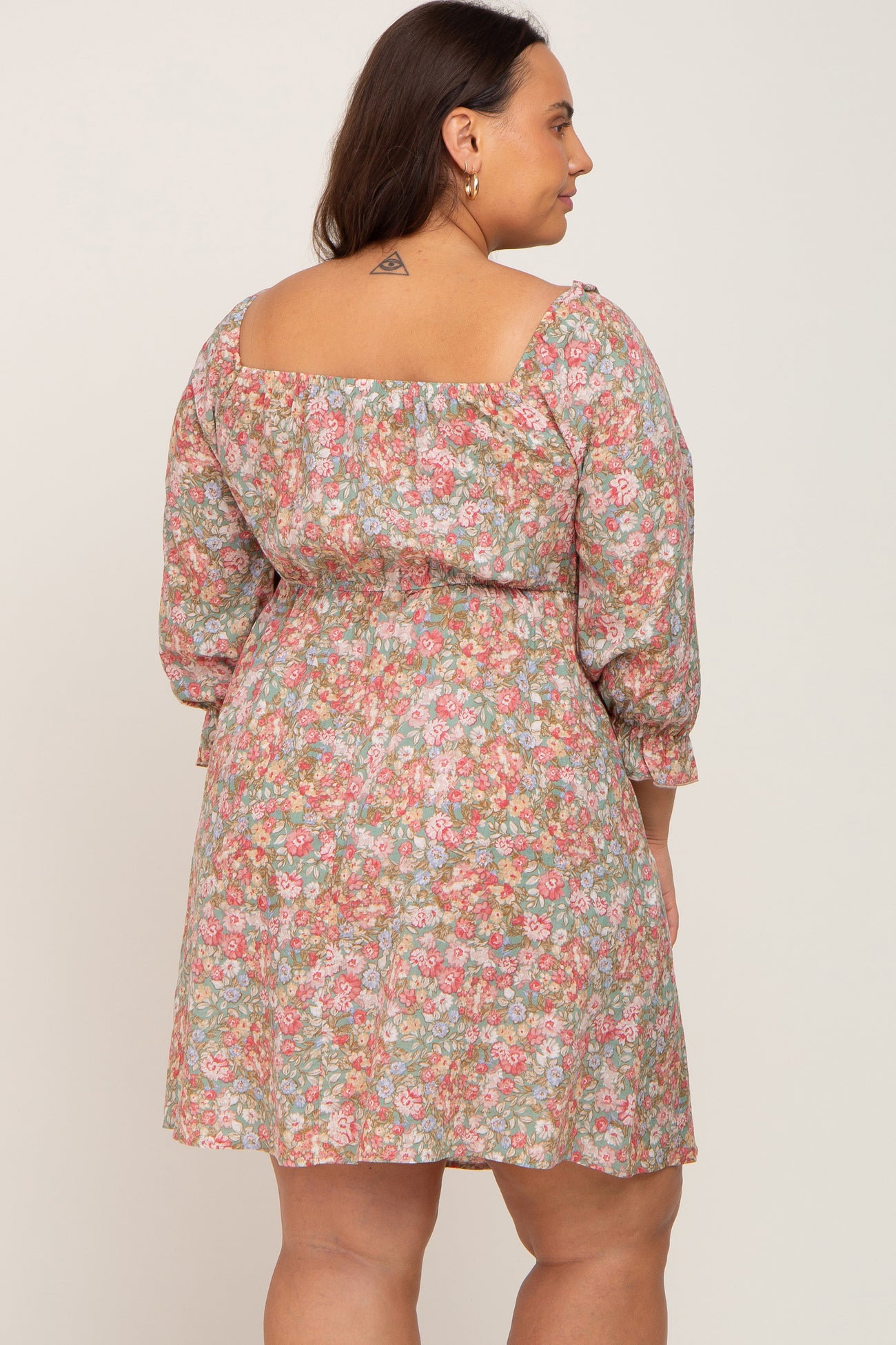 woman wearing a floral print short dress with three-quarter puff sleeves and a square neckline, viewed from the back