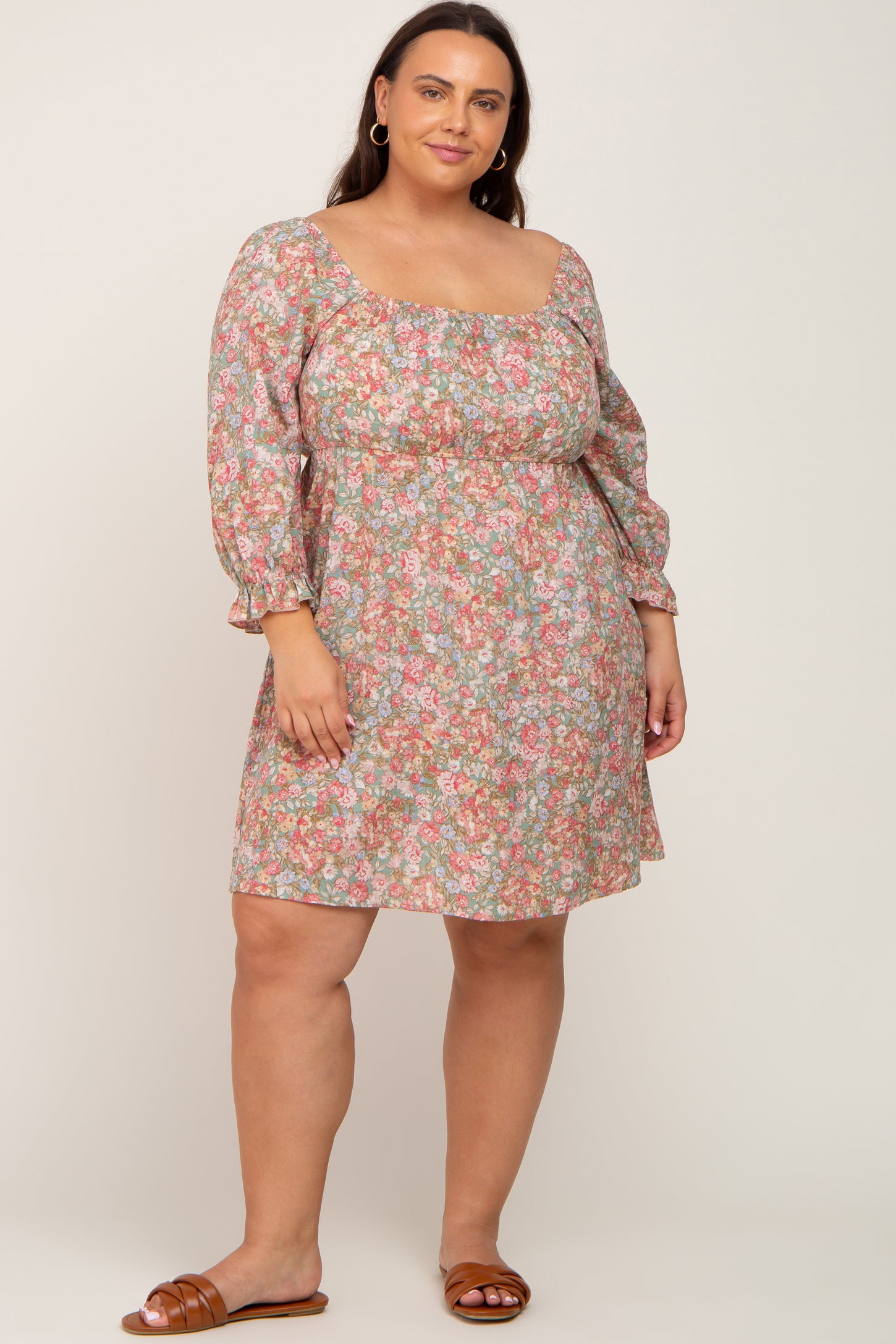 woman wearing a floral print plus size dress with long puff sleeves and a square neckline, standing and smiling