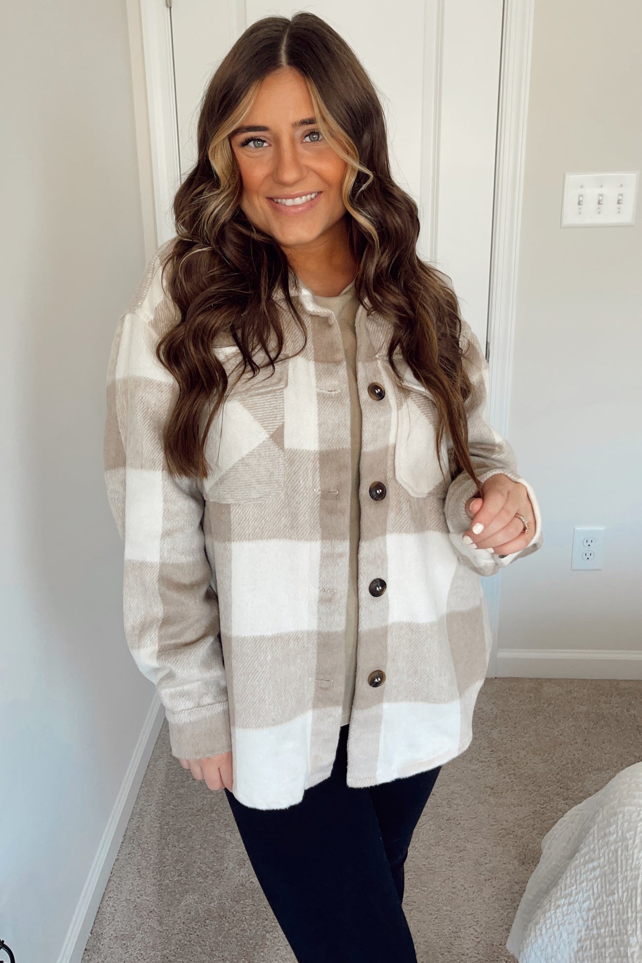 woman wearing a tan and white plaid shacket over a beige shirt and black leggings