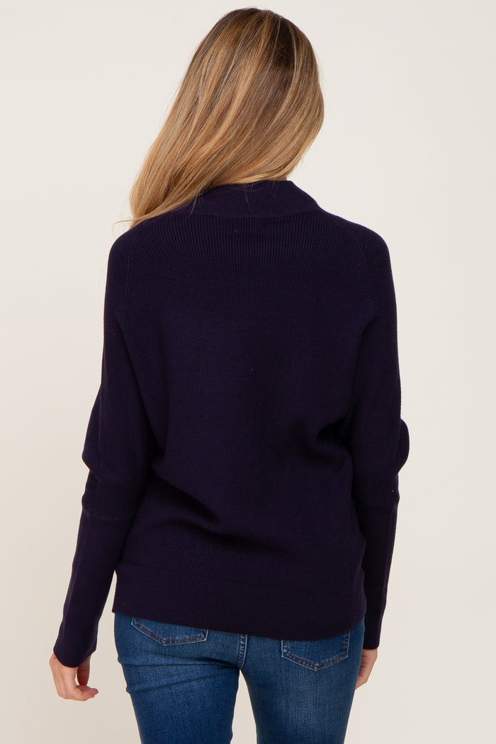 back view of a woman with blonde hair wearing a navy blue ribbed knit sweater and blue jeans