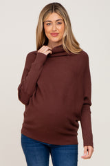 woman wearing a rust colored maternity sweater with a cowl neck and a visible baby bump