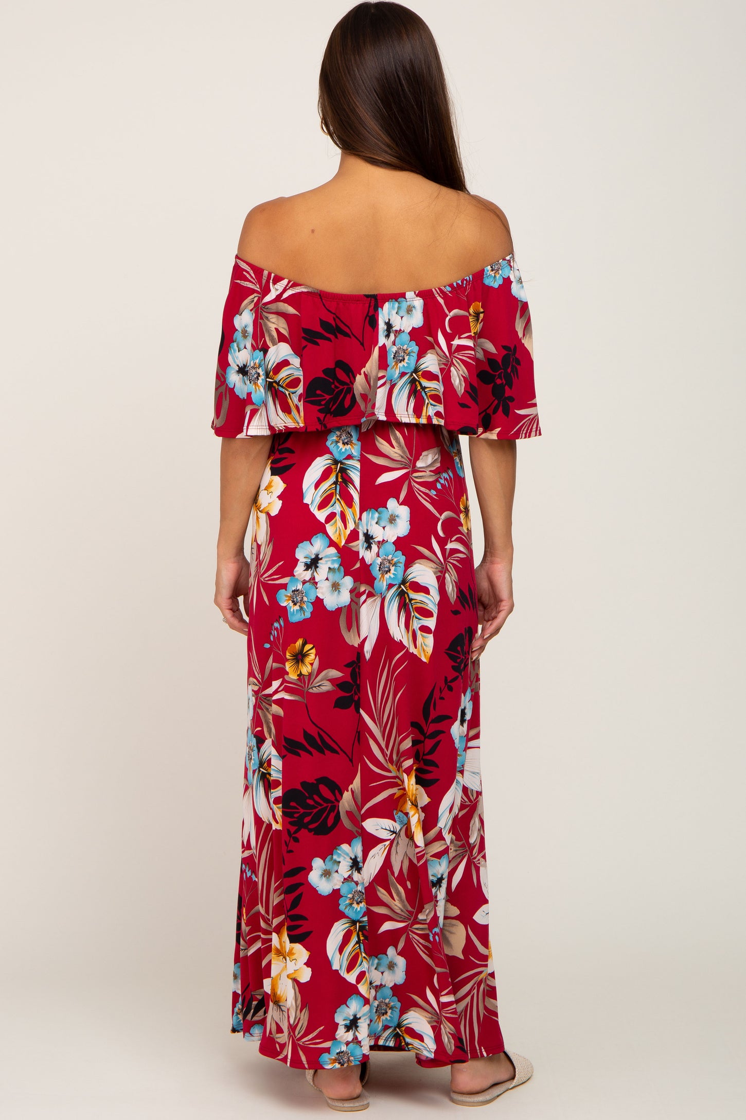 woman wearing a red floral off-the-shoulder maternity maxi dress with a flowing fit