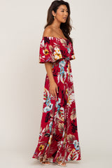 woman wearing a red off-the-shoulder maxi dress with floral print and a flowing skirt