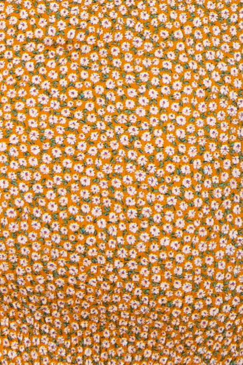 close-up of orange maternity wear fabric featuring a small floral pattern in white and green