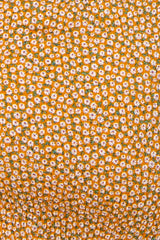 close-up of orange maternity wear fabric featuring a small floral pattern in white and green