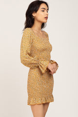 woman wearing a yellow floral mini dress with long bell sleeves and a ruffled hemline