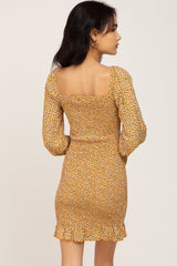 woman wearing a yellow floral mini dress with long sleeves and a square neckline