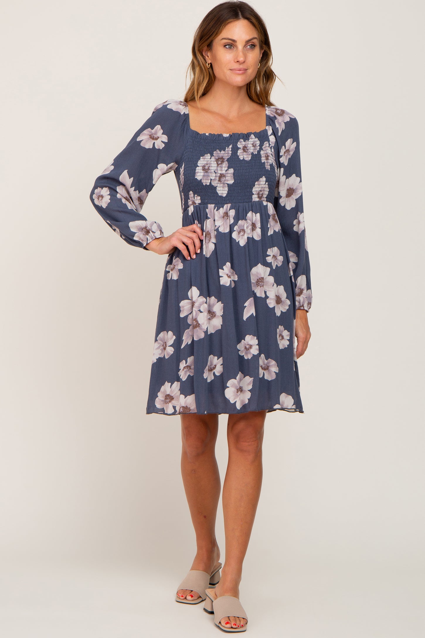 woman wearing a navy floral smocked dress with long sleeves and a square neckline