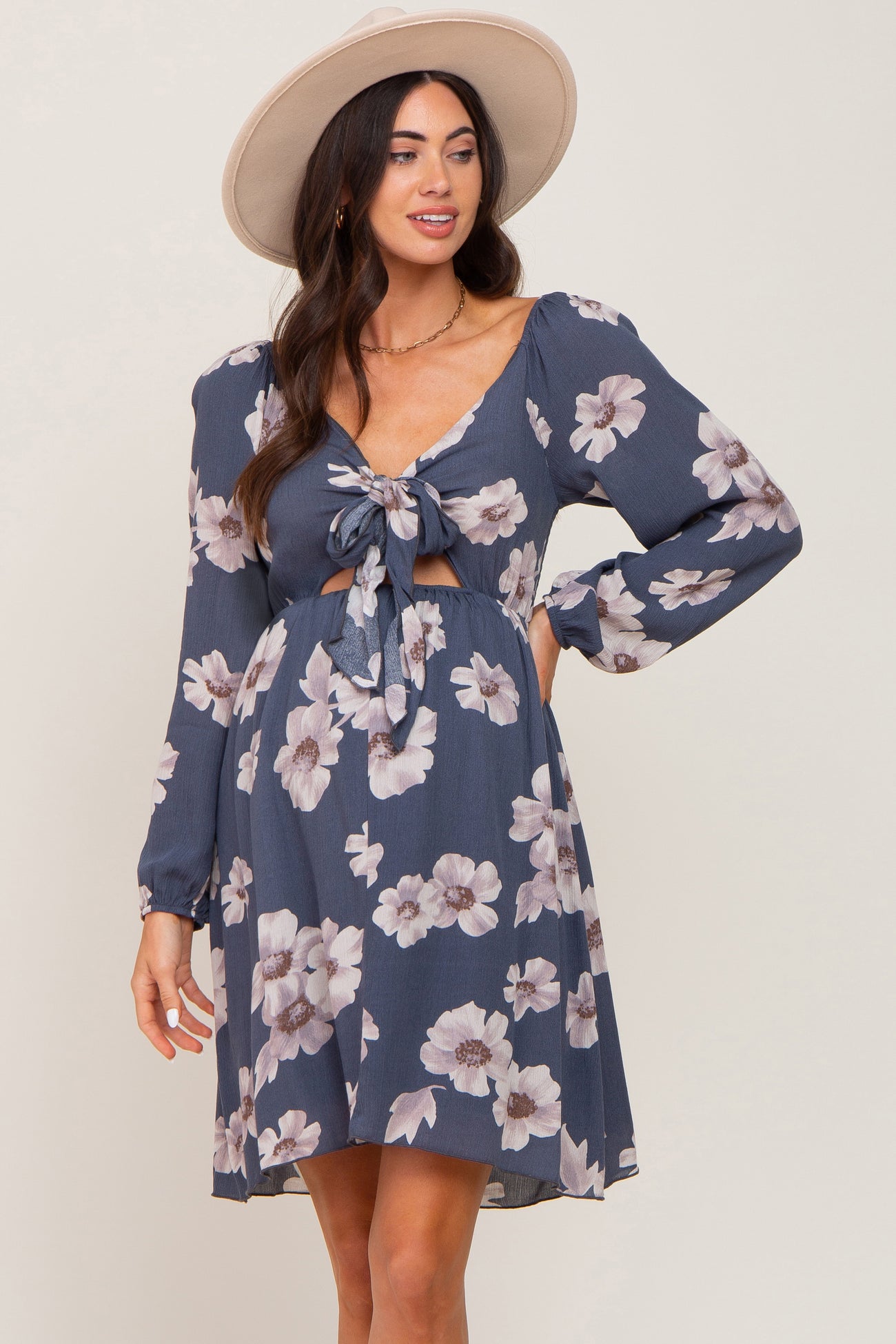 woman wearing a navy floral maternity dress with a tie front and long sleeves, showing her baby bump