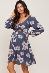 woman wearing a navy blue floral maternity dress with long sleeves and a tie front detail, showcasing her baby bump