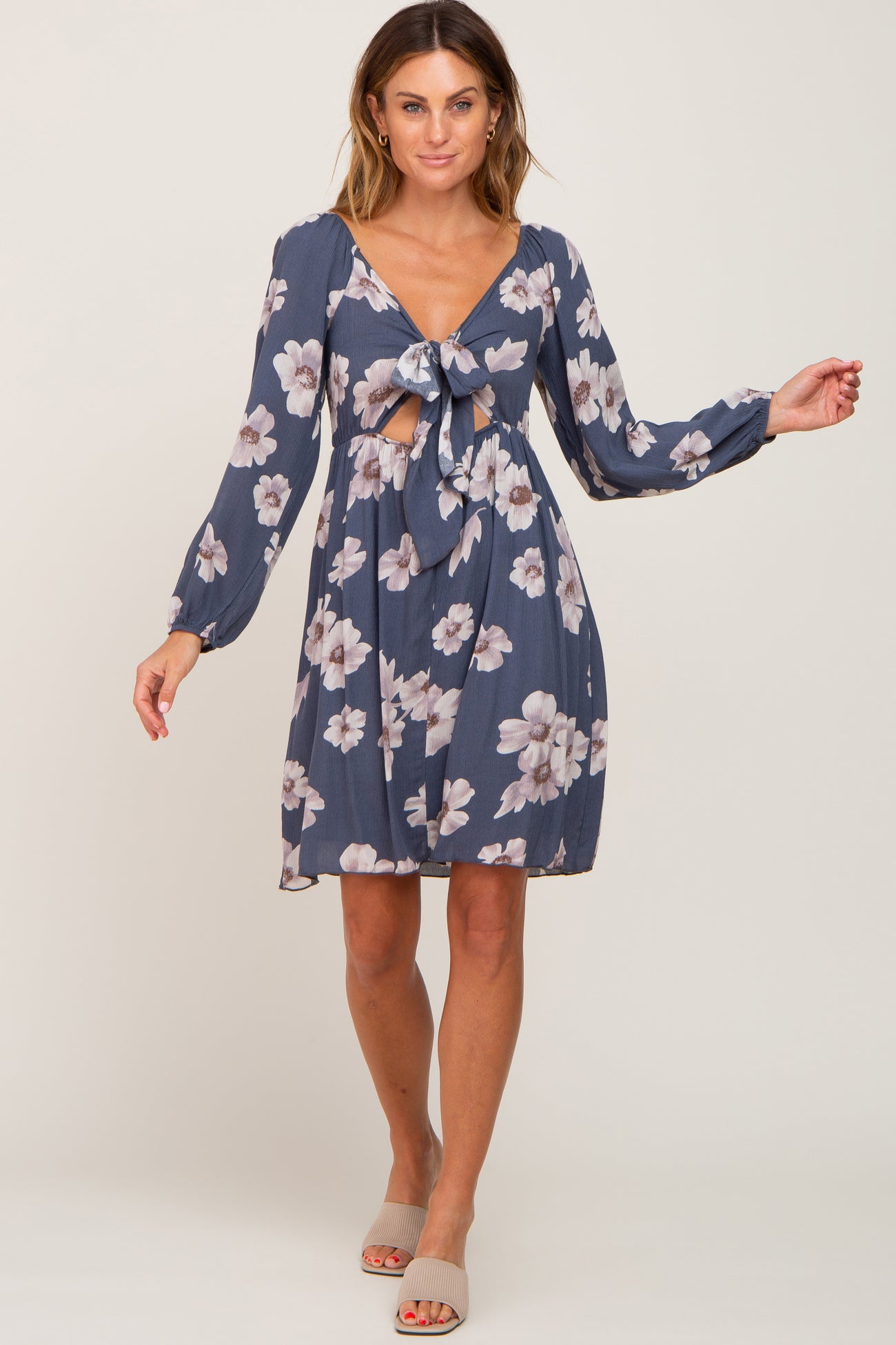 woman wearing a dark blue floral dress with a deep v-neck and tie front detail, posing confidently