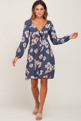 woman wearing a dark blue floral dress with a deep v-neck and tie front detail, posing confidently