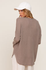 woman wearing a taupe oversized ribbed long sleeve top with side slits and a white baseball cap