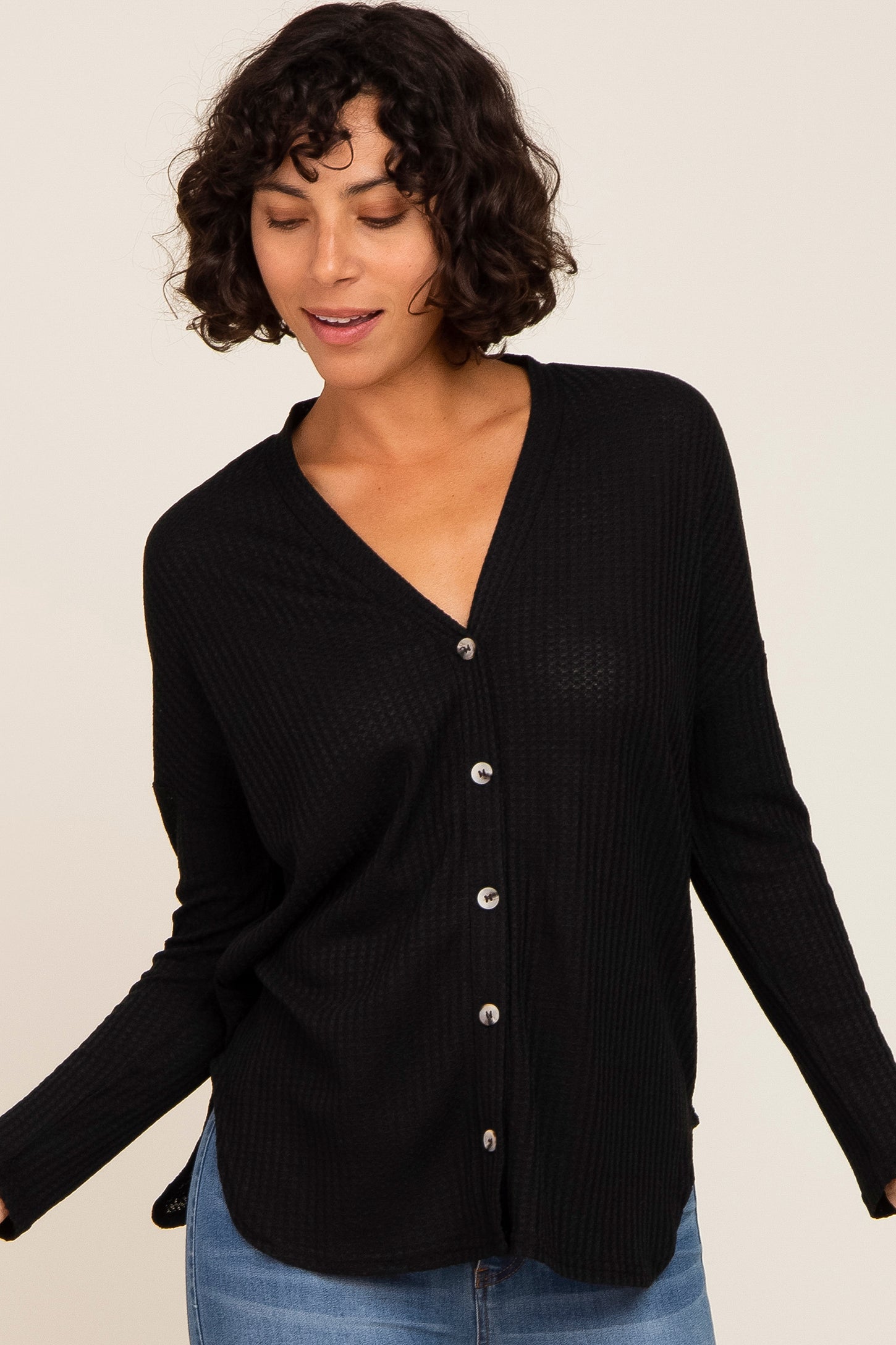 woman wearing a black button-up cardigan with a v-neck and relaxed fit, paired with blue jeans