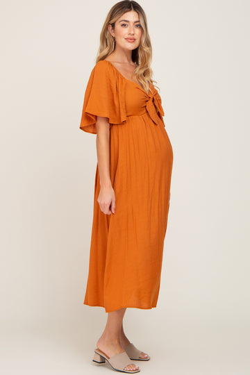 woman wearing an orange maternity maxi dress with a tie front detail and a visible baby bump
