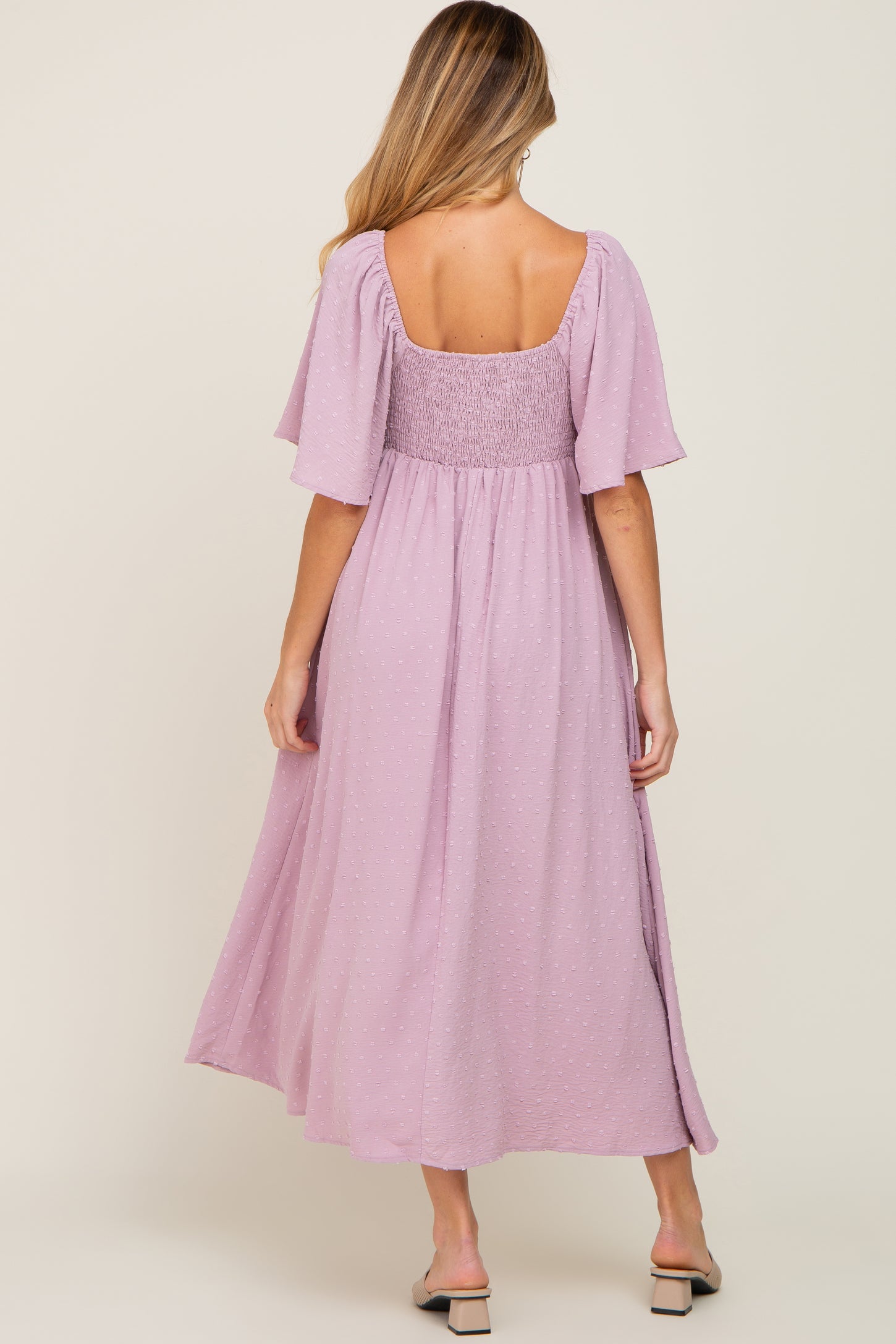 woman wearing a lavender maternity maxi dress with smocked bodice and flutter sleeves, showing her back view