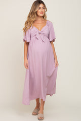 woman wearing a light purple maternity maxi dress with short flutter sleeves and a front tie detail, showing her baby bump