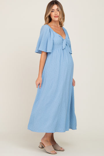 woman wearing a light blue maternity dress with a knot tie detail and flutter sleeves, showing baby bump