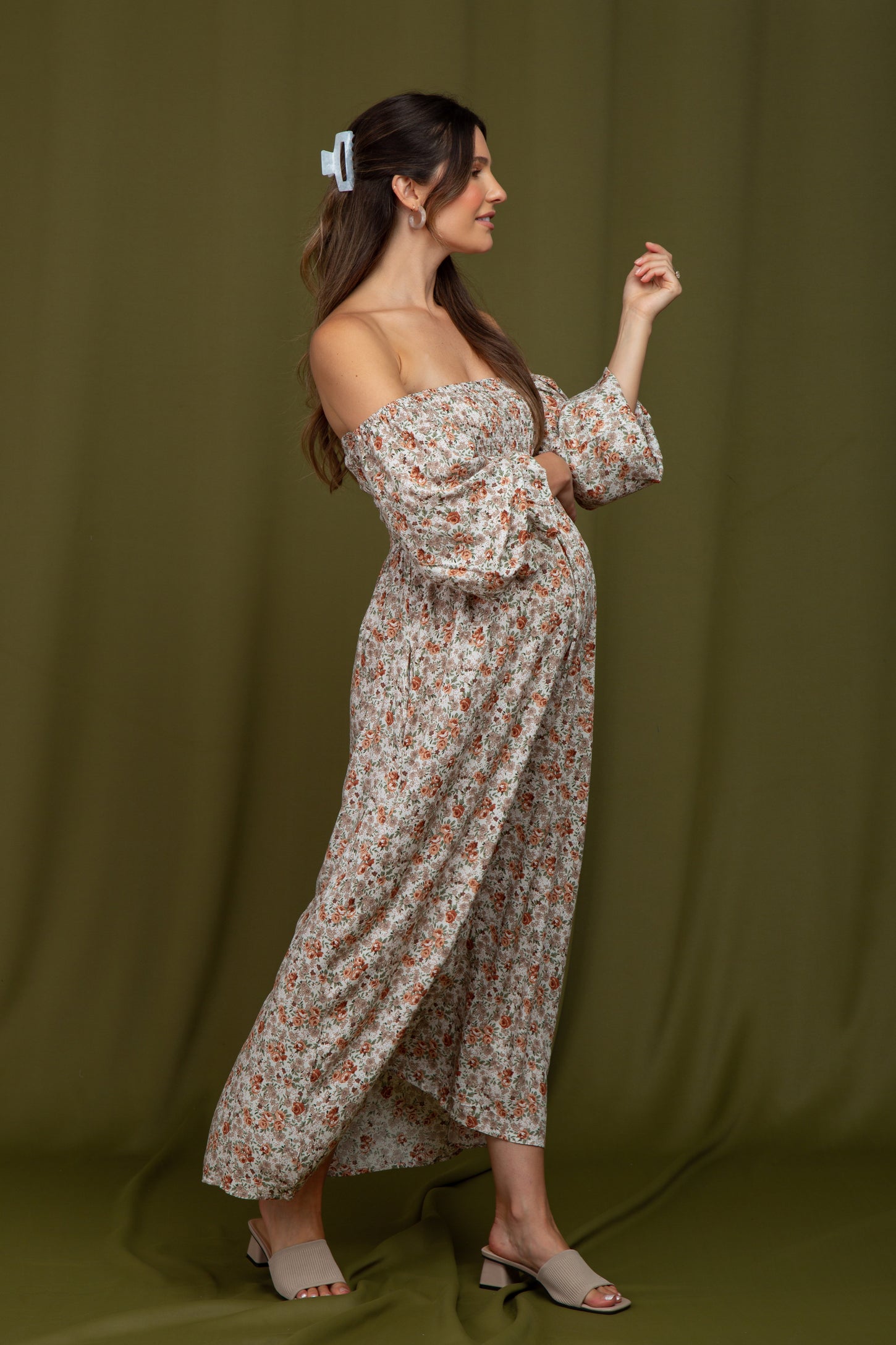 woman wearing a floral off-the-shoulder maternity maxi dress with puff sleeves and a visible baby bump