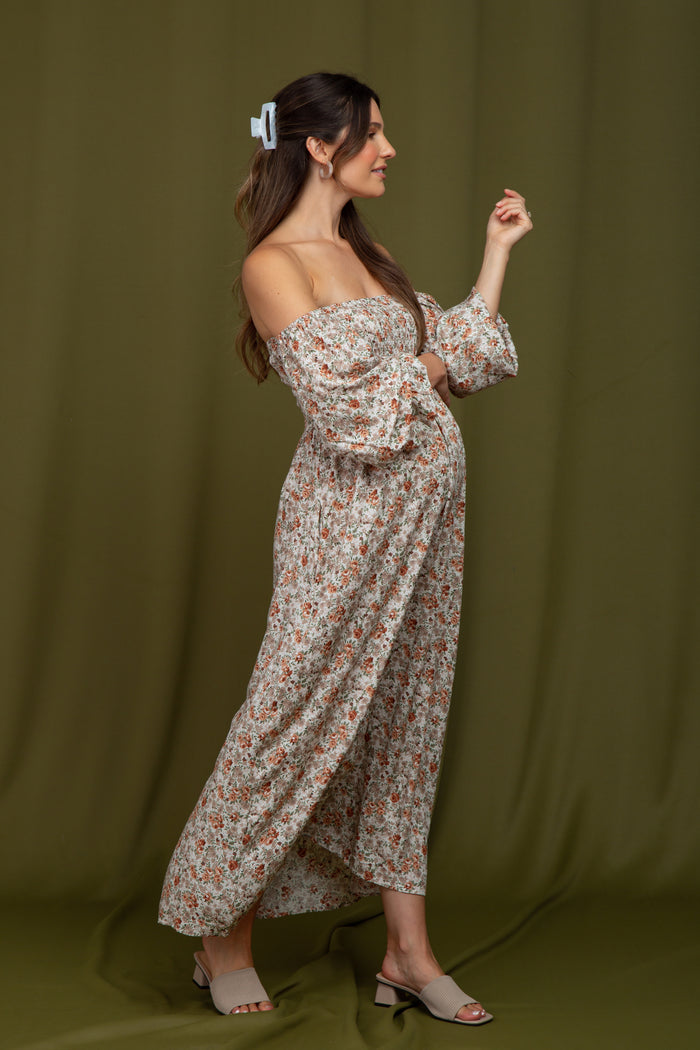 woman wearing a floral off-the-shoulder maternity maxi dress with puff sleeves and a visible baby bump