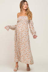 woman wearing a floral off-shoulder maternity maxi dress with long sleeves and a baby bump visible