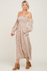 woman wearing a floral off-the-shoulder maxi dress with long sleeves and a fitted bodice, paired with brown ankle boots