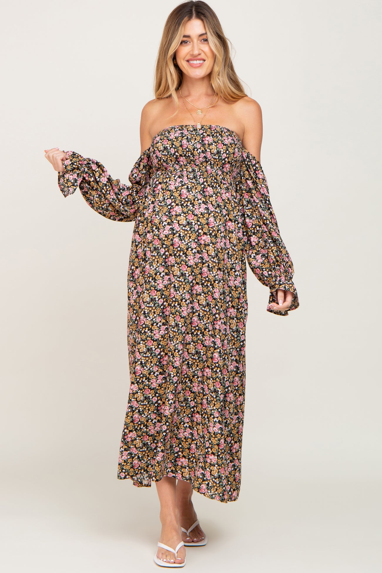 woman wearing a floral off-the-shoulder maxi maternity dress with long sleeves and visible baby bump