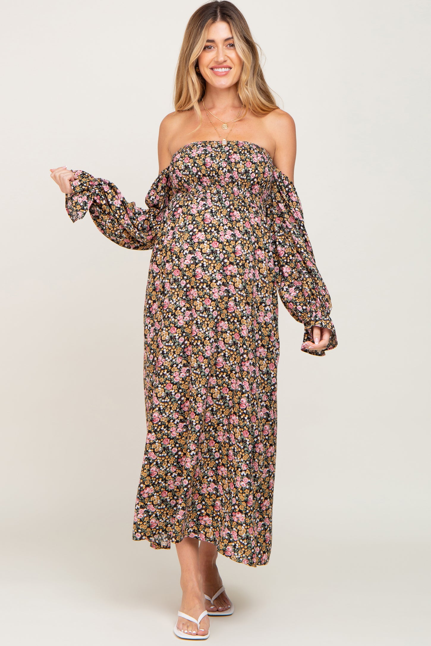woman wearing a floral off-the-shoulder maxi maternity dress with long sleeves and visible baby bump