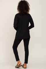woman with curly hair from behind wearing black long sleeve ribbed top and matching leggings with sandals
