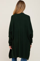 woman wearing a long green maternity cardigan, view from the back, with loose fit and ribbed texture