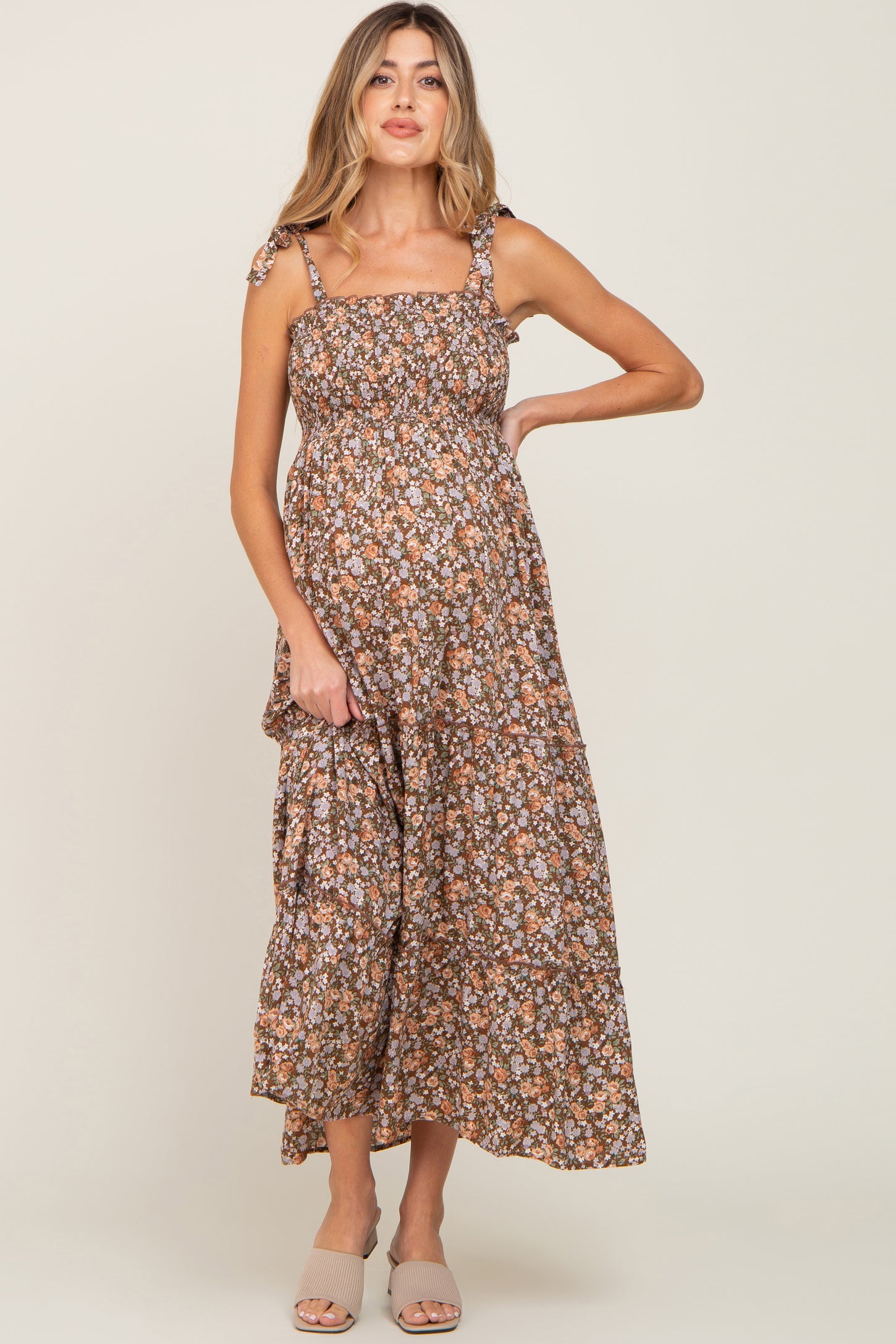 woman wearing a brown floral maternity maxi dress with adjustable straps and a visible baby bump