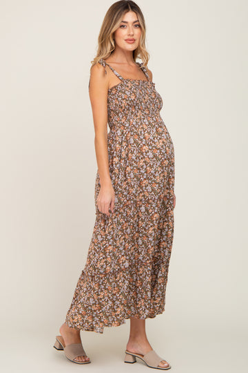 woman wearing a brown floral maternity maxi dress with tied straps and a visible baby bump