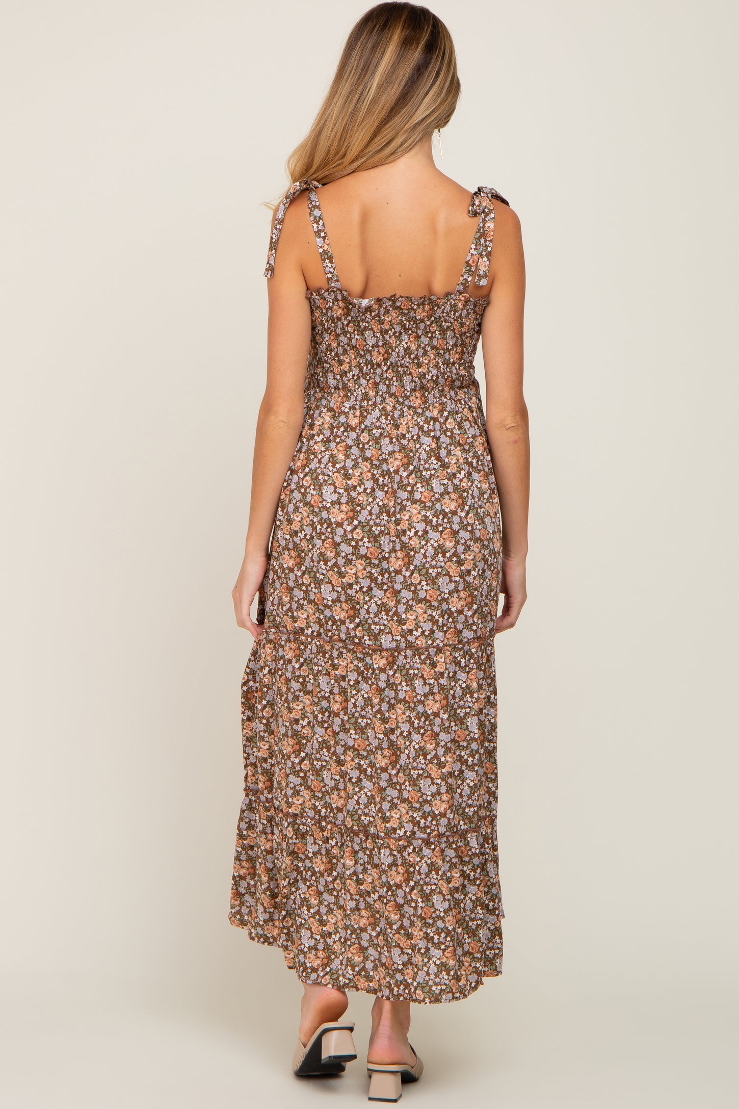 woman wearing a floral print brown maternity maxi dress with tie straps and smocked back
