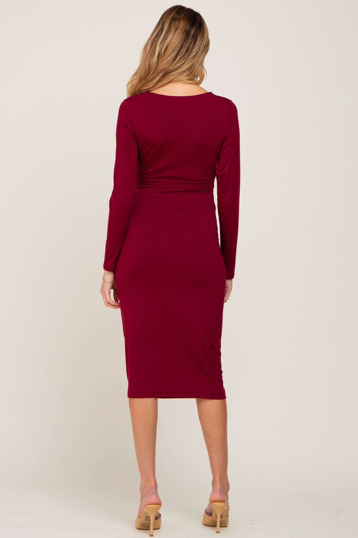 woman wearing a burgundy long sleeve fitted maternity dress from the back