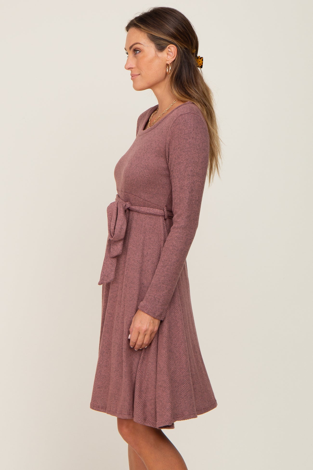woman wearing a mauve long sleeve sweater dress with a tie waist detail and a flared skirt