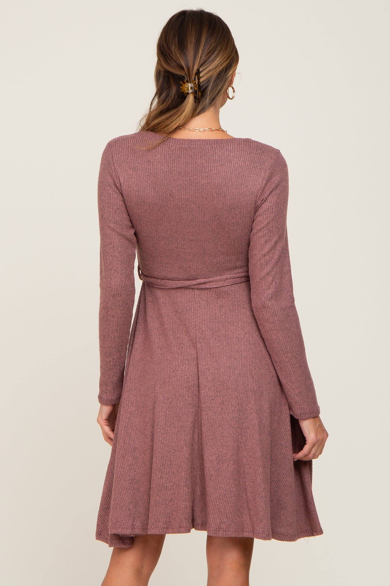 woman wearing a mauve long sleeve ribbed dress with a fitted bodice and flared skirt