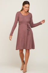 woman wearing a mauve long sleeve sweater dress with a belted waist and a flared skirt
