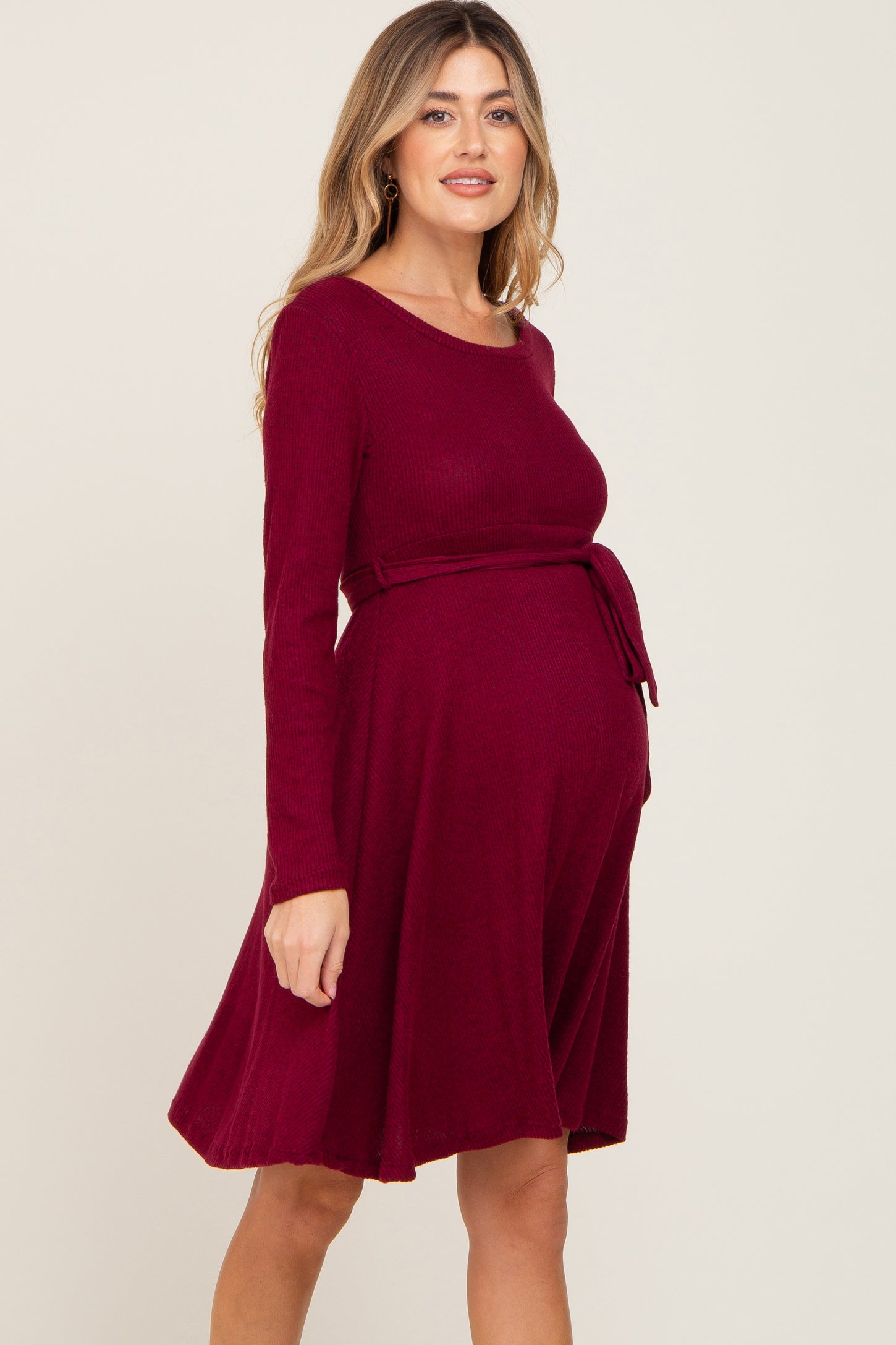woman wearing a burgundy long sleeve maternity dress with a tie waist and a visible baby bump