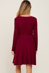 back view of a woman wearing a long sleeve burgundy ribbed knit maternity dress