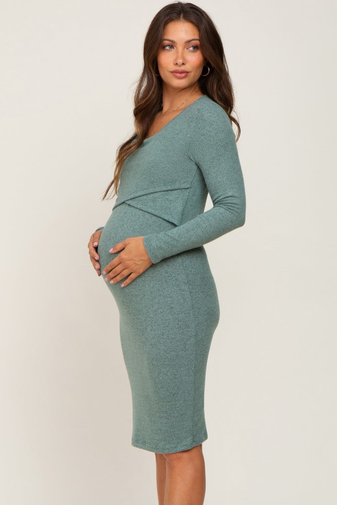 Pregnant woman wearing a long sleeve sage green maternity dress with a crossover bust detail