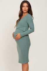 Pregnant woman wearing a long sleeve sage green maternity dress with a crossover bust detail