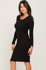 woman wearing a black long sleeve fitted dress with a scoop neckline and seam detail