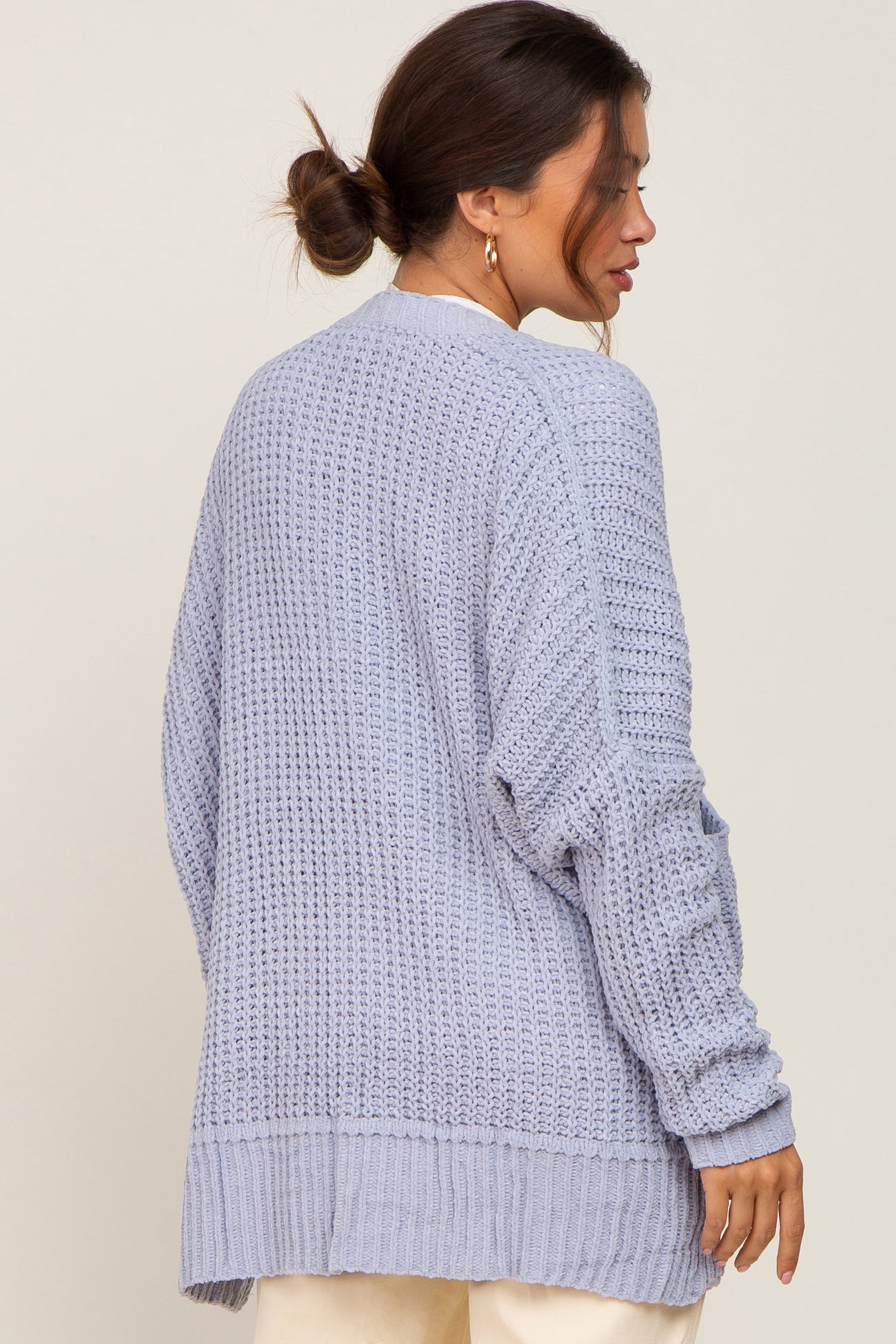 Woman wearing a light blue oversized chunky knit cardigan sweater from the back