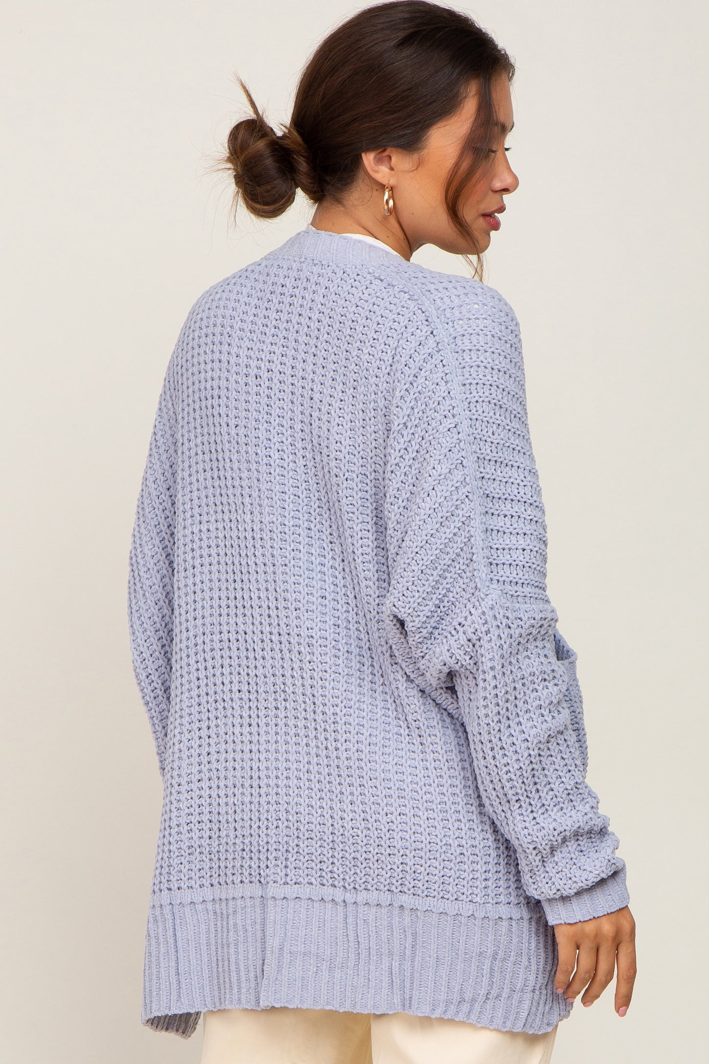 Woman wearing a light blue oversized chunky knit cardigan sweater from the back