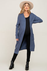 woman wearing a navy blue long sleeve maternity cardigan with pockets and black pants, showing her baby bump