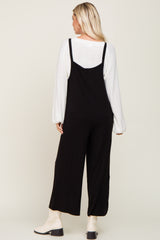 woman wearing a black jumpsuit with wide legs, seen from the back, paired with cream ankle boots and a white long sleeve top