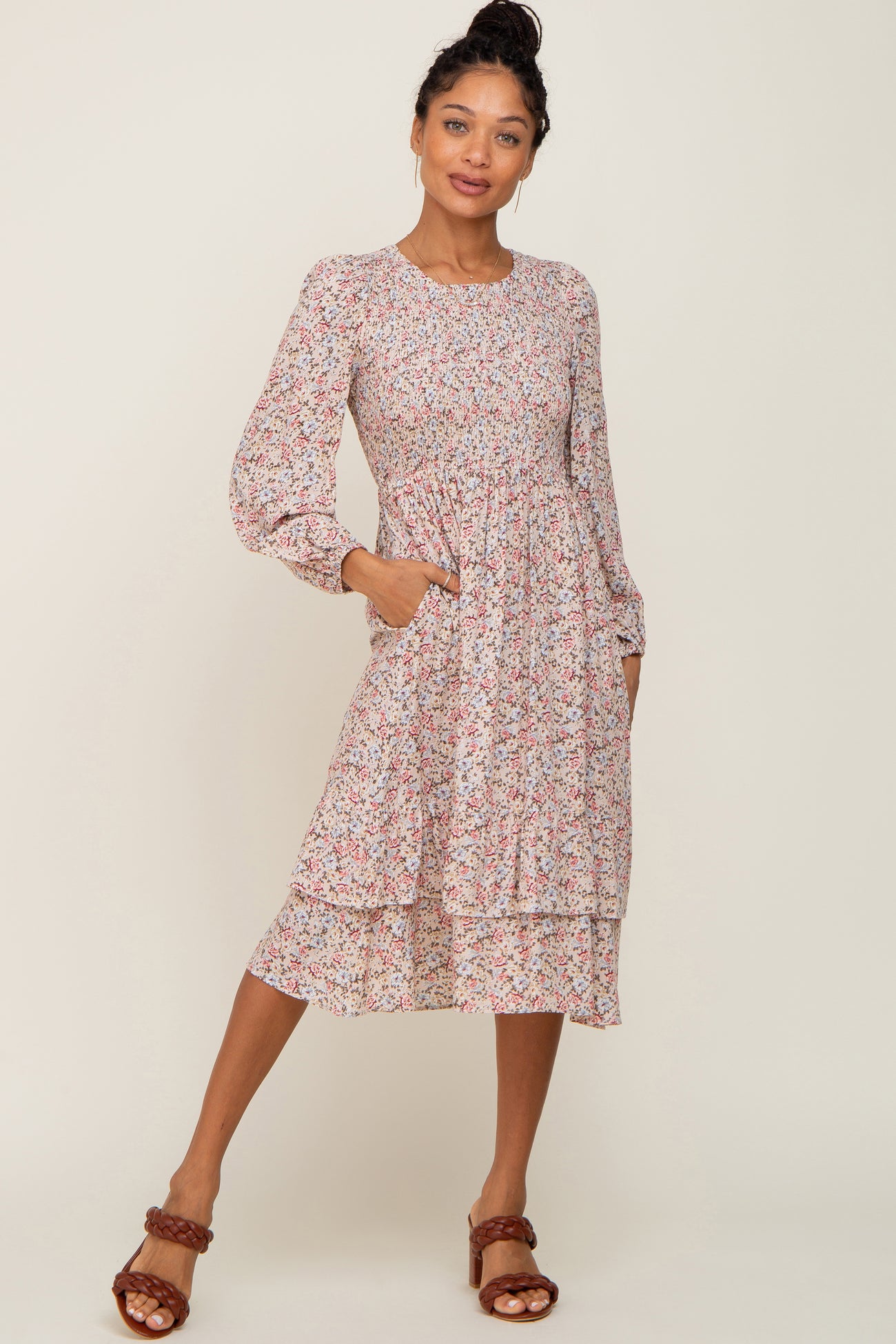 Woman wearing a long sleeve floral smocked midi dress with tiered skirt and brown braided heels