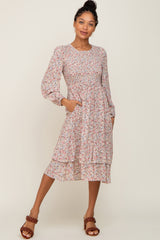Woman wearing a long sleeve floral smocked midi dress with tiered skirt and brown braided heels