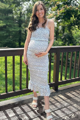 woman wearing a floral print maternity dress with ruffles and holding her baby bump